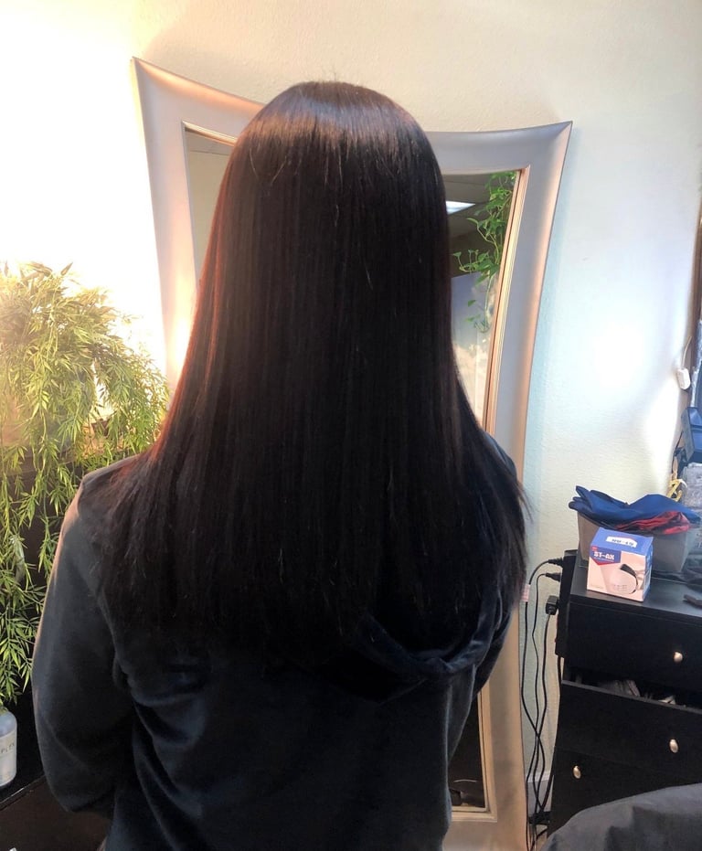 Person with long dark hair viewed from behind, standing in front of a mirror