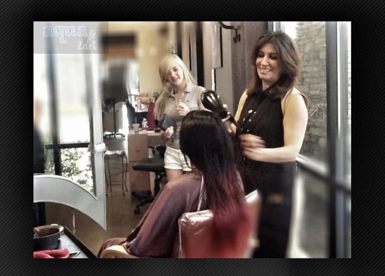 Hairstylist styling clients hair in a salon with another stylist visible in background